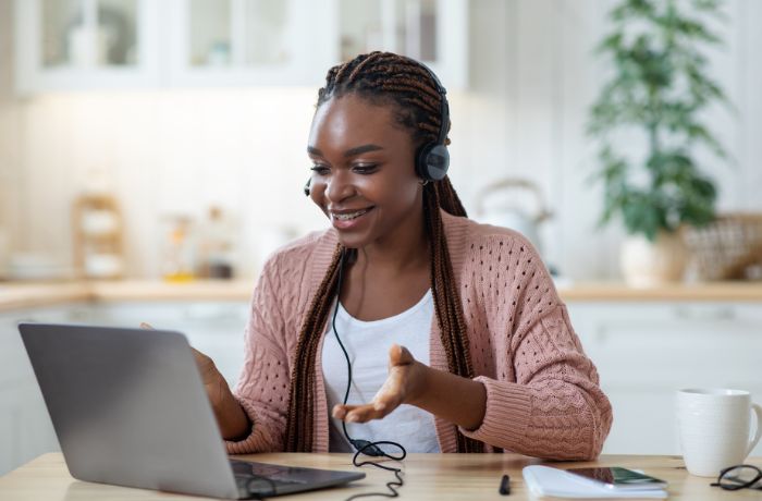 Smiling black female tutor using laptop in kitchen