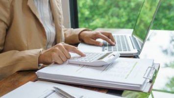 Hands calculating costs using a laptop and calculator