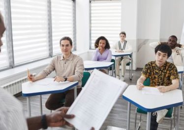 Students Sitting Inside the Classroom while Looking at their Teacher